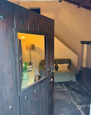 Une porte en bois sombre avec une petite fenĂȘtre, une lampe, un canapĂ© et un escalier Ă lâarriĂšre-plan.