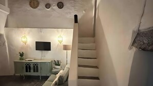 A cozy living room with a staircase, a sofa, a TV, and a cabinet.