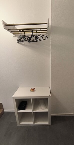 Ein weißer Lagerraum mit Regalen und einer Kleiderstange.