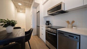 A modern kitchen with a dining area, including a table with chairs, a microwave, stove, oven, and dishwasher.