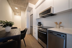 A modern kitchen with a dining area, including a table with chairs, a microwave, stove, oven, and dishwasher.