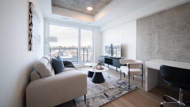 A modern living room with a sofa, chairs, a coffee table, and a TV.