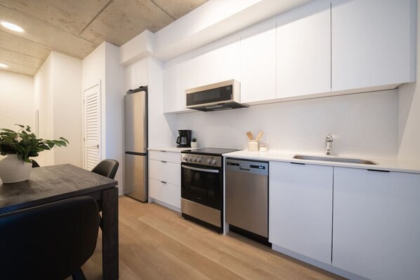 Une cuisine moderne avec des meubles blancs, un four à micro-ondes, une cuisinière et un lave-vaisselle.