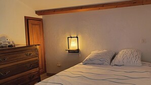 A bedroom with a wooden dresser, a wall-mounted light, and a shelf with a plush toy. - Stone village house in the heart of nature and 15 minutes from the beaches (Conca)