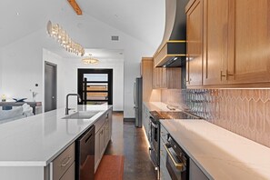 Une cuisine moderne dotée d’un îlot central, d’appareils électroménagers en acier inoxydable et de meubles de rangement en bois.