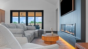 Una sala moderna con un sofá modular, una mesa de centro redonda y una chimenea.