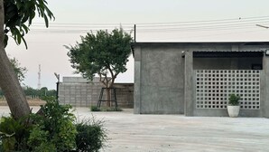 A concrete building with a garage door, a tree, and a potted plant.