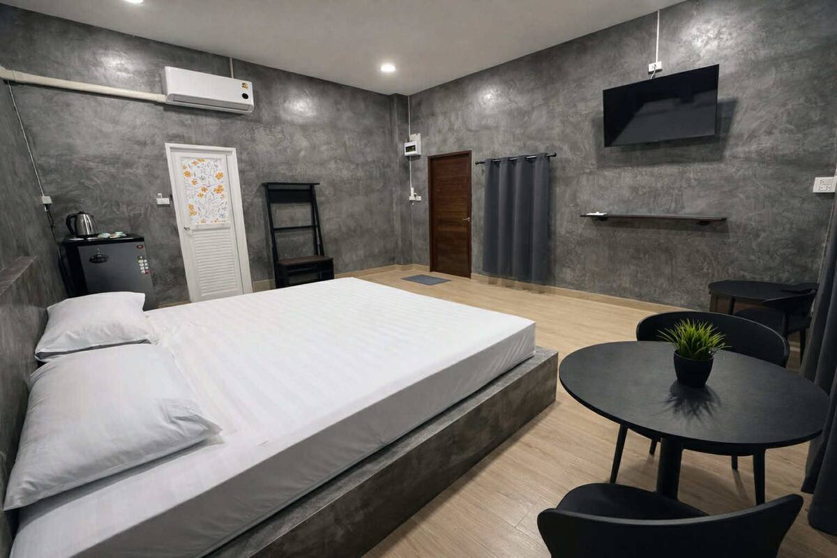 Ein modernes Schlafzimmer mit einem Bett, einem Nachttisch und einem kleinen, runden Tisch mit einer Pflanze.