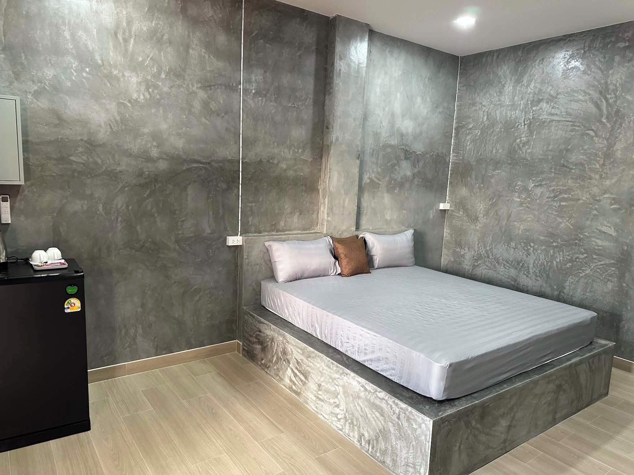 A modern bedroom with a bed, a nightstand, and a wall-mounted light fixture.