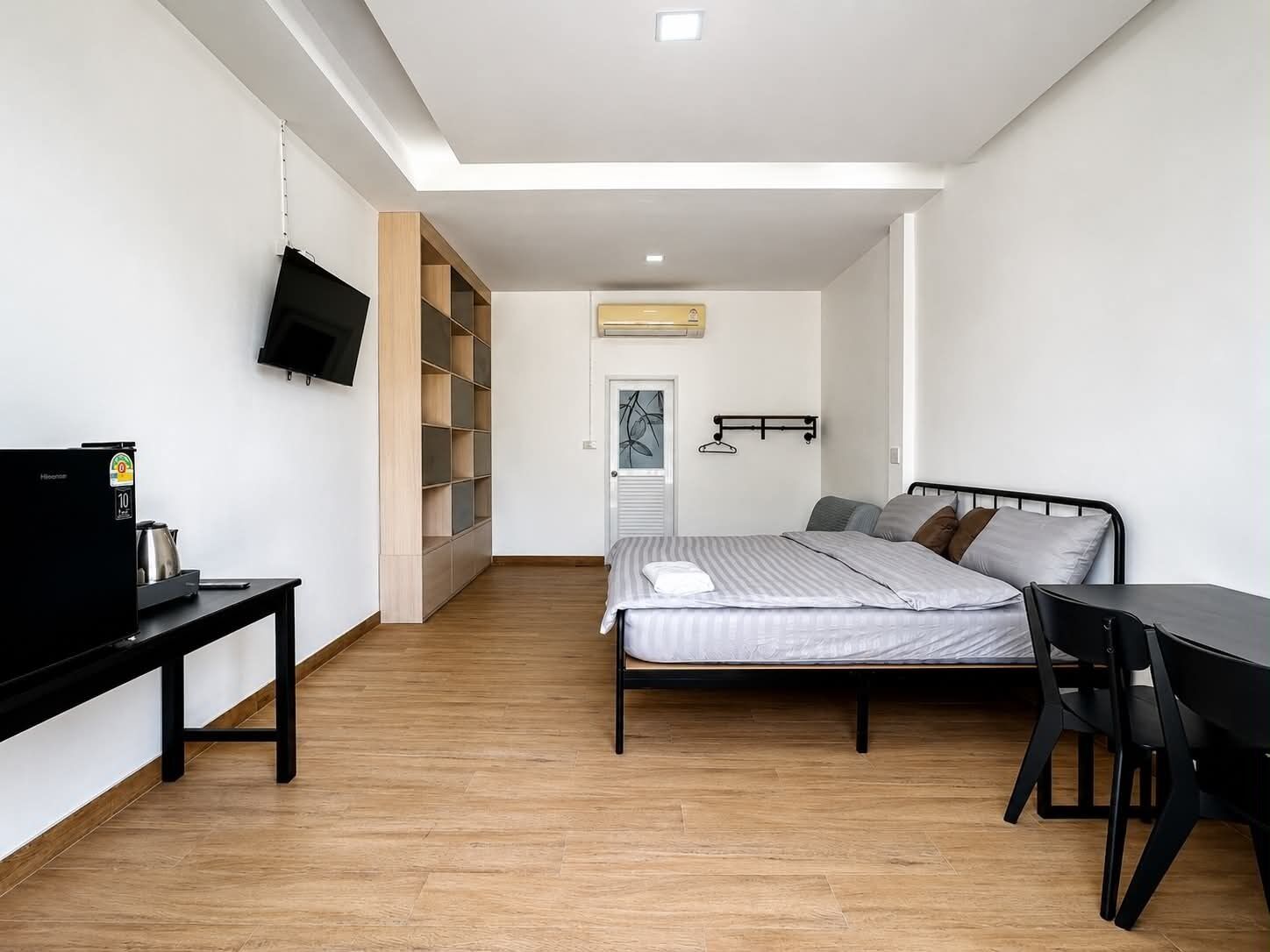 Un dormitorio con cama, escritorio, silla, televisor y armario.