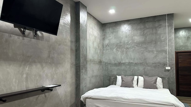 A modern bedroom with a bed, a mounted TV, and a minimalist design.