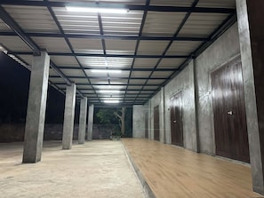 A covered corridor with concrete pillars, wooden flooring, and metal-framed ceilings. - Baan Puen Kin Kanchanaburi (Tha Muang)