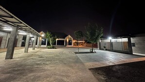 A spacious outdoor area with a covered walkway, a building with large windows, and a fenced section.