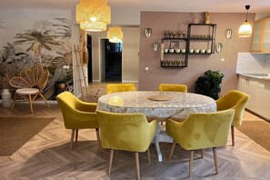 A dining area with a round table, yellow chairs, and a patterned wall.
