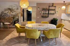 A dining area with a round table, yellow chairs, and a patterned wall with wall-mounted shelves. - Comfortable Jacuzzi Apartment for 8 in Stezyca (Stezyca)
