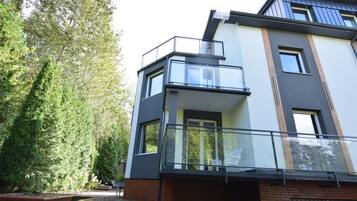 A modern two-story residential building with a balcony and a visible door.
