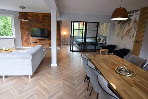 A modern living room with a sofa, a dining table, and a TV.