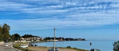A coastal road with cars, a clear sky, and a distant shoreline.