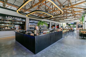 A modern bar area with a central counter displaying various bottles, surrounded by seating and other restaurant sections. - Pool with Sea View | 200MB WIFI | Foodhall #TT405 (Florianópolis)