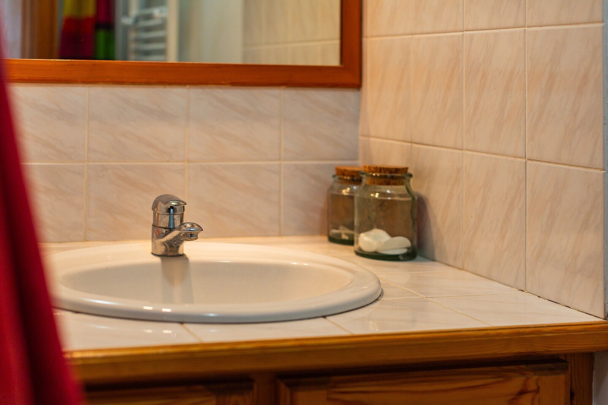 A bathroom with a sink, mirror, and two glass jars with white objects.