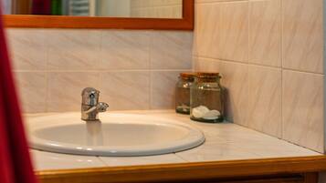 A bathroom with a sink, mirror, and two glass jars with white objects.