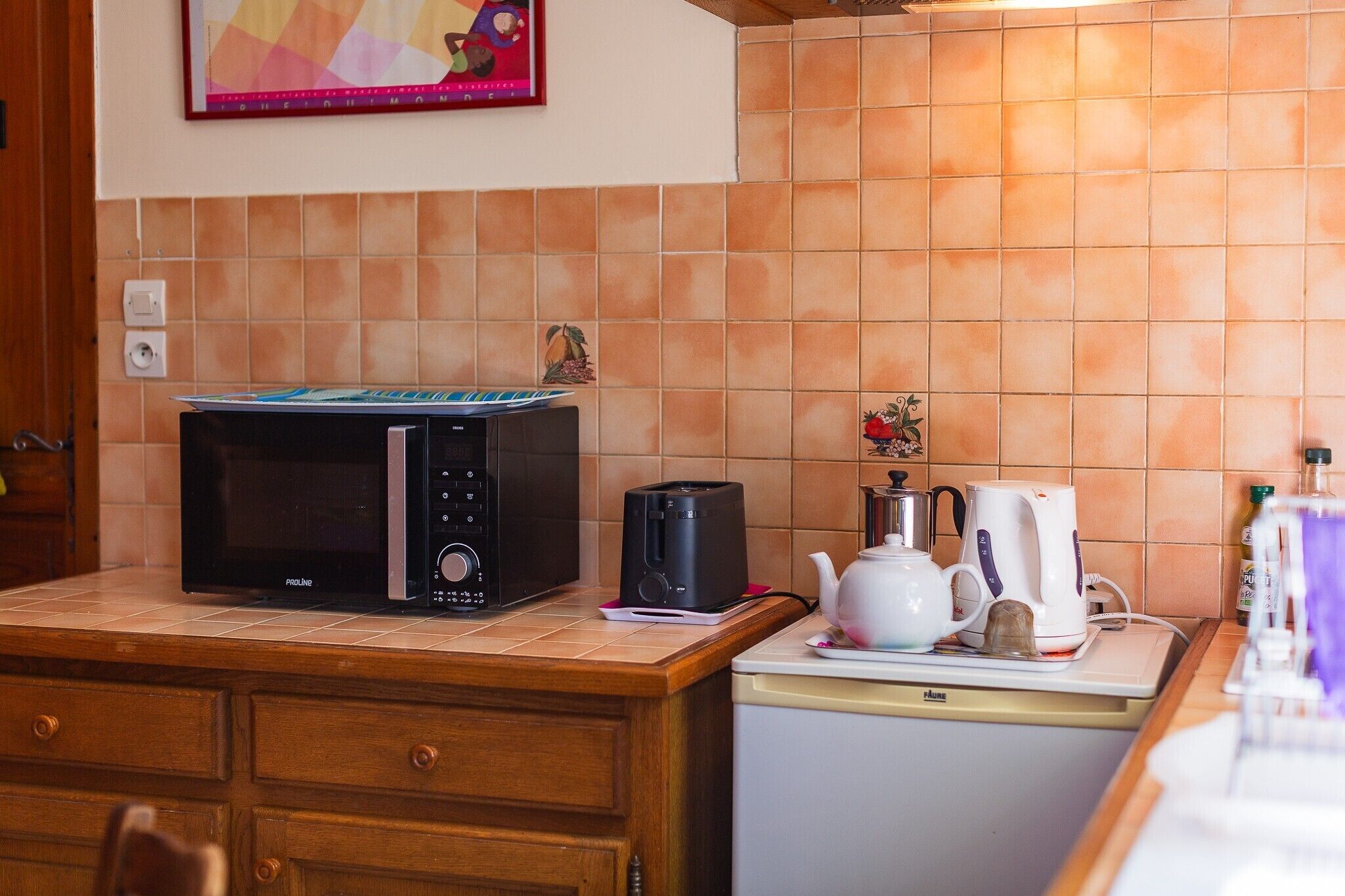 A kitchen with a microwave, a coffee maker, and a small refrigerator.