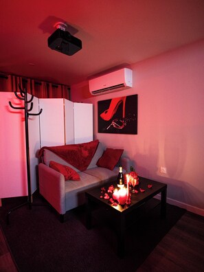 En moderne stue med en sofa, et sofabord med stearinlys og en aircondition på væggen.