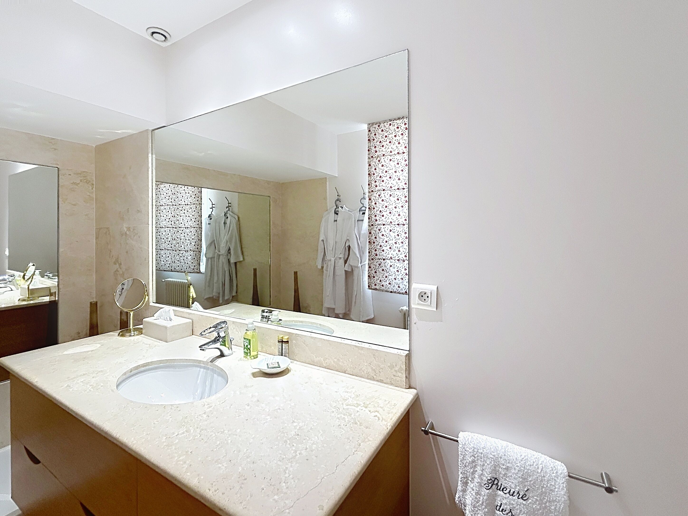 Un baño con un espejo grande, un lavabo y un perchero para toallas.