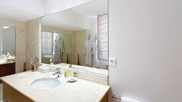 Un baño con un espejo grande, un lavabo y un perchero para toallas.