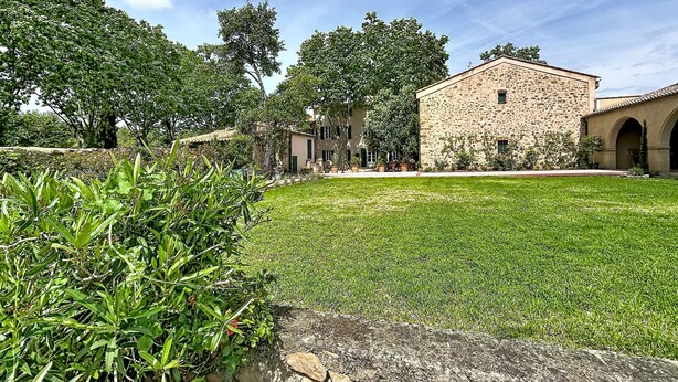 Un edificio de piedra con un patio central, rodeado de follaje y árboles.