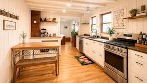 A kitchen with wooden cabinets, a stove, a sink, and a coffee machine. - Sunapee Shore and Summit (Newbury)