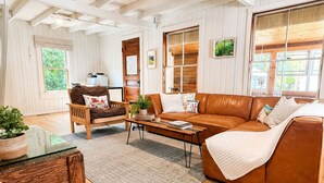 A spacious living room with a brown leather sofa, wooden coffee table, and a glass-top side table. - Sunapee Shore and Summit (Newbury)