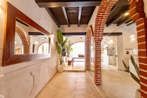 A hallway with brick arches, a potted plant, and a glimpse of a dining area. - Casa Sol - Villa in Getsemaní with Large Pool (Cartagena)