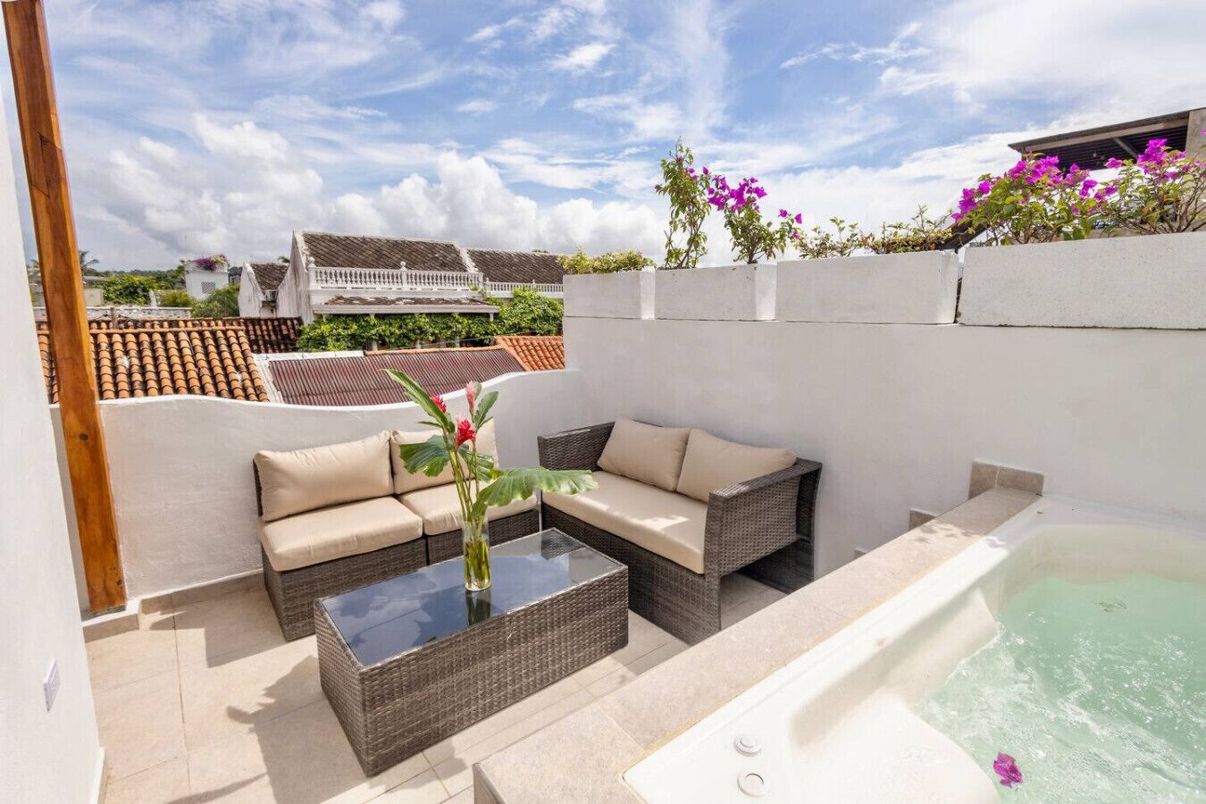 Eine Terrassengruppe im Freien mit einer Sitzecke, einem Tisch mit Glasplatte und einem Whirlpool.