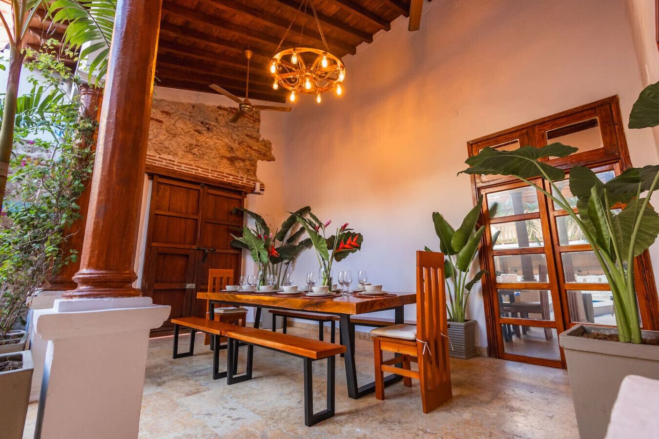 Un comedor con una mesa de madera, sillas y plantas en macetas.