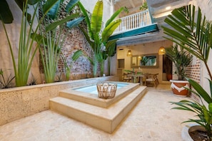 Un'area benessere con una piscina in pietra, scalini adiacenti e rigogliosa vegetazione tropicale.