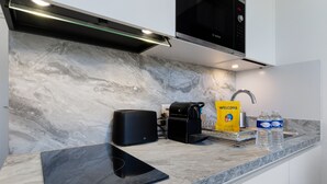 Een moderne keuken met een marmeren spatwand, een Bosch magnetron, een koffiezetapparaat en een welkomstbord.