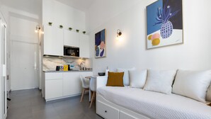 Een moderne keuken met witte kastjes, een marmeren aanrechtblad en een eethoek met een witte tafel en stoelen.