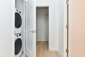 Una sala de lavandería con dos lavadoras y una puerta que da a un pasillo.