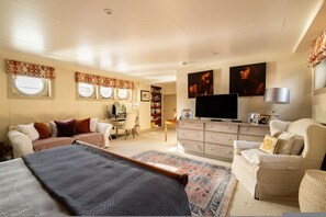 Ein geräumiges Schlafzimmer mit einem großen Bett, einem Schreibtisch, einem Fernseher und einem Sofa.