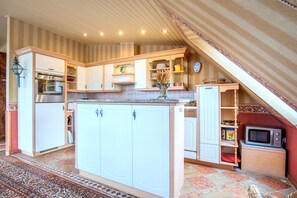 A kitchen with white cabinets, a built-in oven, a microwave, and a small refrigerator. - Apartment Meerblick 17 with Sea View and Private Rooftop Terrace (Binz)