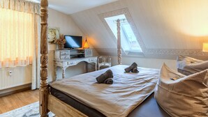 Un dormitorio con cama, escritorio, televisor y ventana.