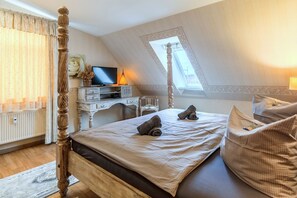 A bedroom with a bed, a desk, a television, and a window. - Apartment Meerblick 17 with Sea View and Private Rooftop Terrace (Binz)