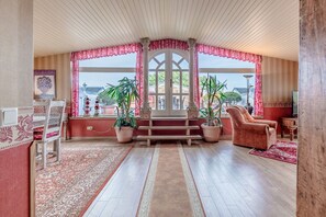 A room with a wooden floor, a red and white patterned rug, a wooden bench, a pink chair, and potted plants. - Apartment Meerblick 17 with Sea View and Private Rooftop Terrace (Binz)