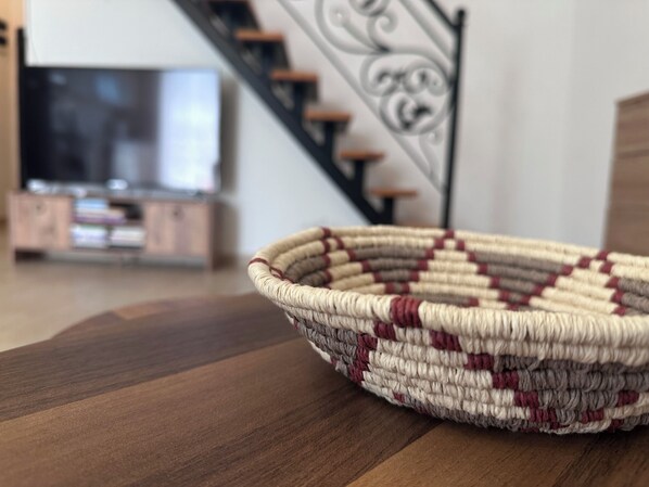 A woven basket on a wooden surface with a staircase and a television in the background. - Kaş Old Town Aparts (Kas)