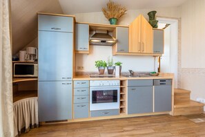 A compact kitchen with a built-in oven, a microwave, and a dishwasher. - Wolke 7 Apartment 18 with Sea View and Private Rooftop Terrace (Binz)