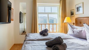 Een hotelkamer met een bed, een raam met gordijnen, een lamp en een televisie aan de muur.