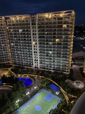A multi-story hotel with a basketball court and pool area.