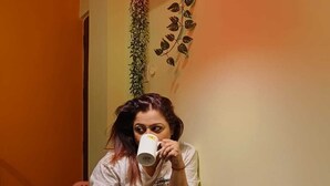 A person sitting at a table with a cup, a small bottle, and a smartphone. - The Soft Light Studio (Hyderabad)