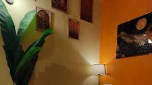 A living room with a sofa, a lamp, a large potted plant, and wall art. - The Soft Light Studio (Hyderabad)